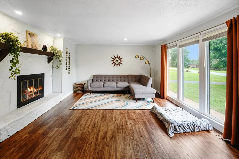 Bright living room with fireplace, large windows, and hardwood floors in Nashville, TN home