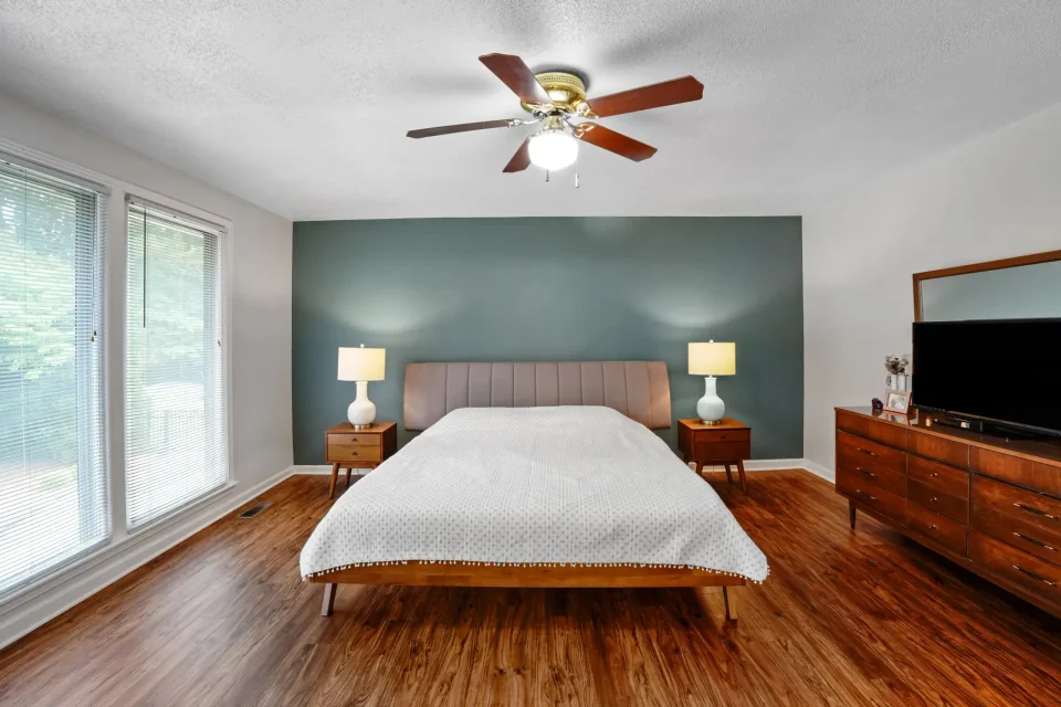 Modern primary bedroom with ceiling fan, wood floors, and natural light in Nashville home