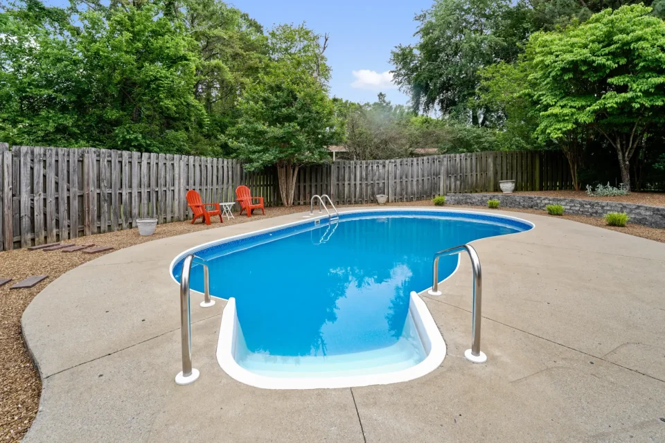 Private backyard with in-ground swimming pool, concrete patio, and wood privacy fence in Tennessee home
